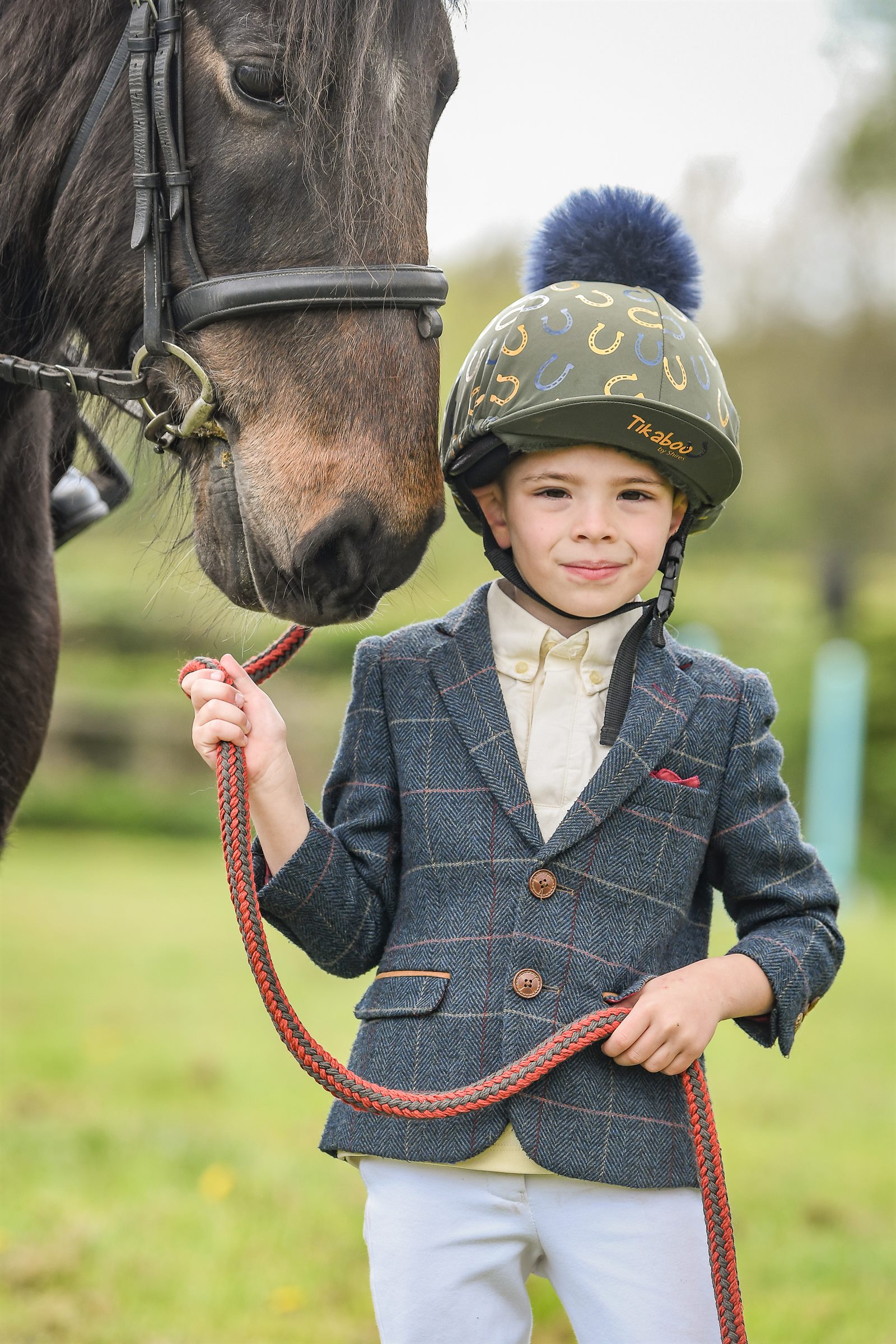 A young club member standing beside a horse