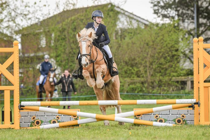 A young rider and pony clearing a colourful showjumping fence